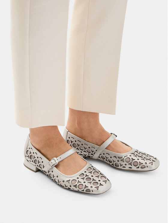 Modelka prezentująca płaskie buty z paskiem, widok na nogi z góry.
