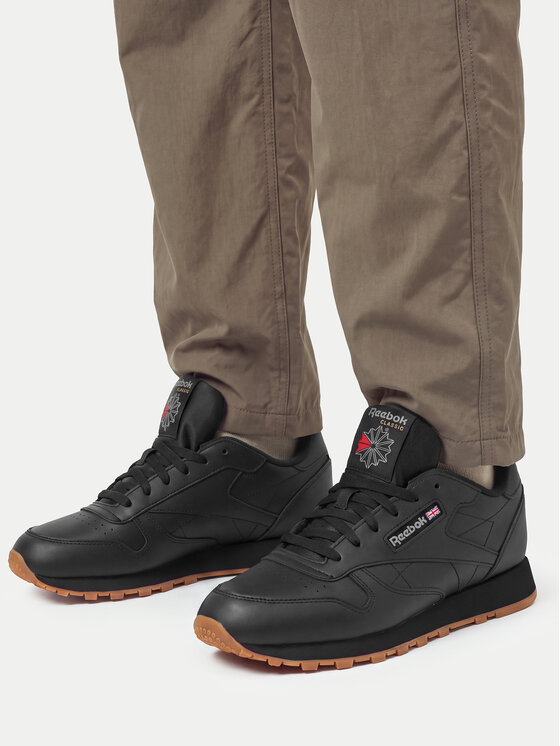 Stopy modela w długich spodniach prezentujące sportowe buty na nogach.