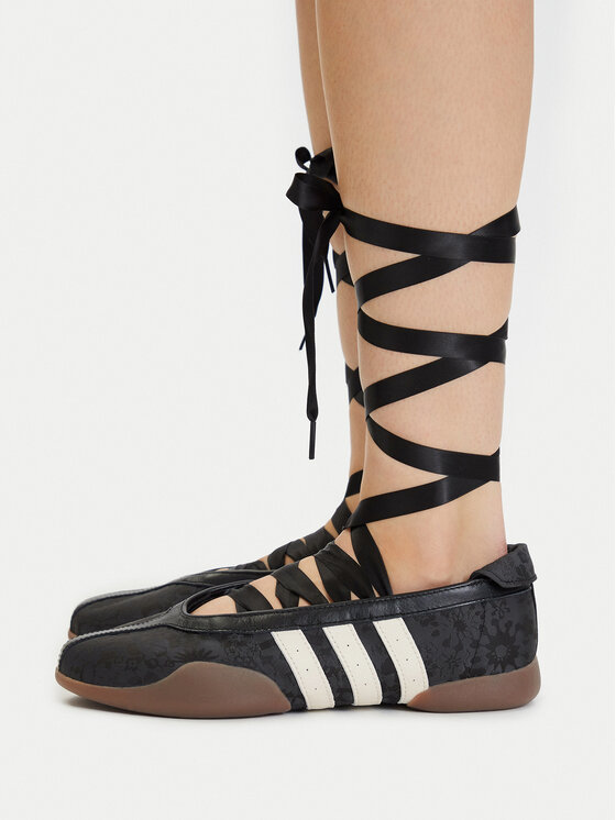Modelka prezentująca buty, widok z boku na nogi i obuwie.