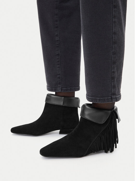 Buty na stopach modelki, ujęcie boczne od dołu nogawek spodni.